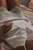 Woman laying down in a satin slip dress with lace detailing